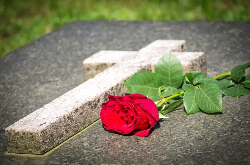a monument stone with a red rose laying beside it with final expense burial life insurance