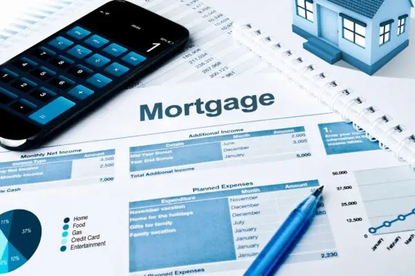 term life insurance calculator sitting on a pile of mortgage paperwork which insinuates you should include your mortgage when considering how much term insurance you need.